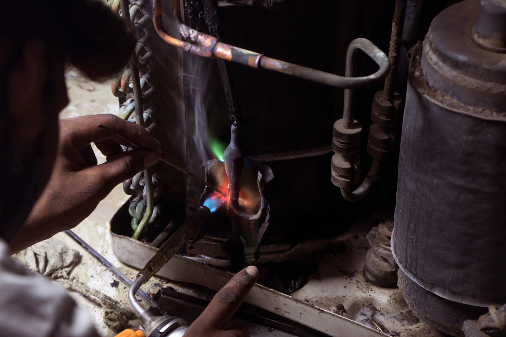Welder performing metal fabrication work with visible blue and orange flames from welding torch