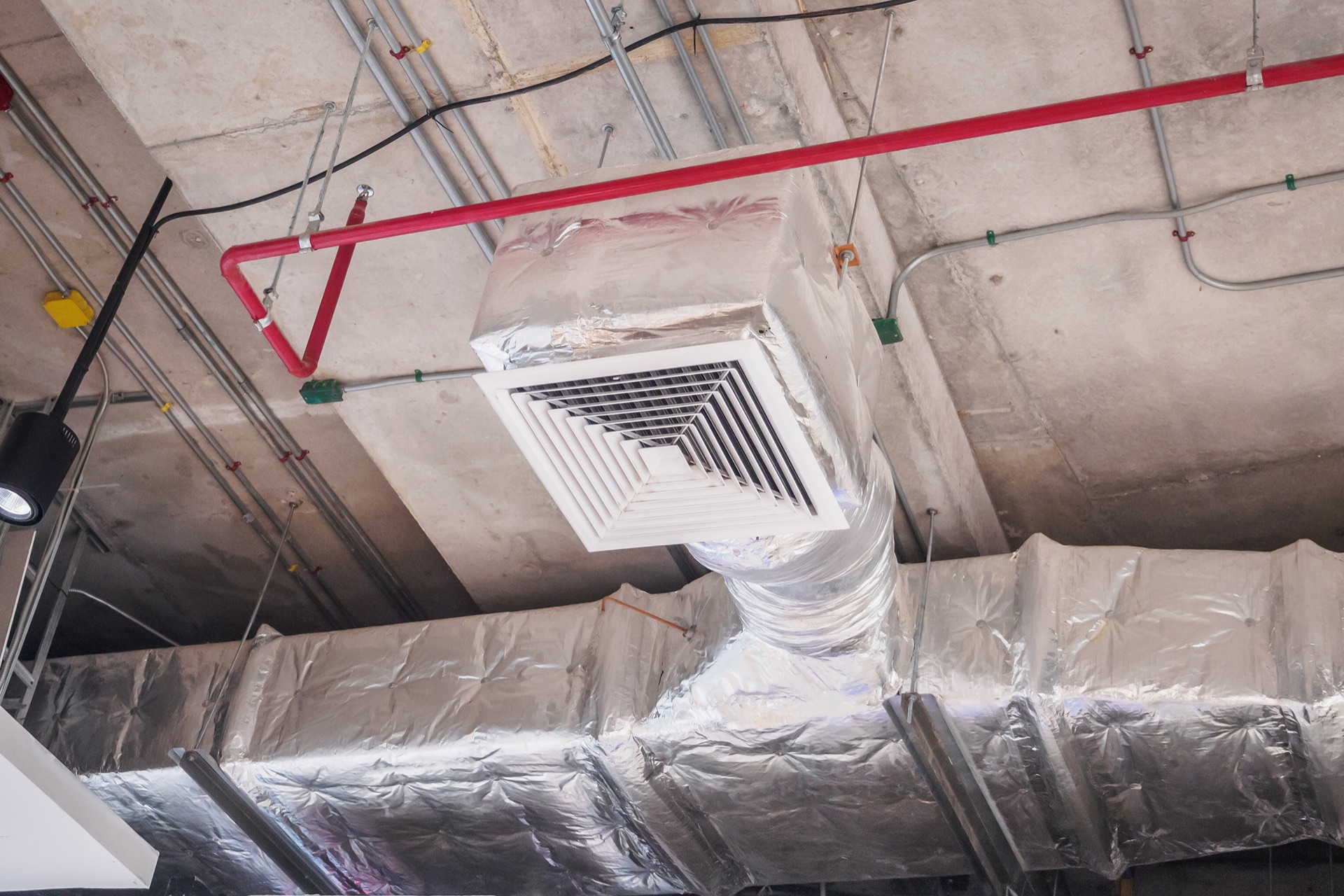 HVAC ductwork installation with insulation wrapping and ventilation grille during construction
