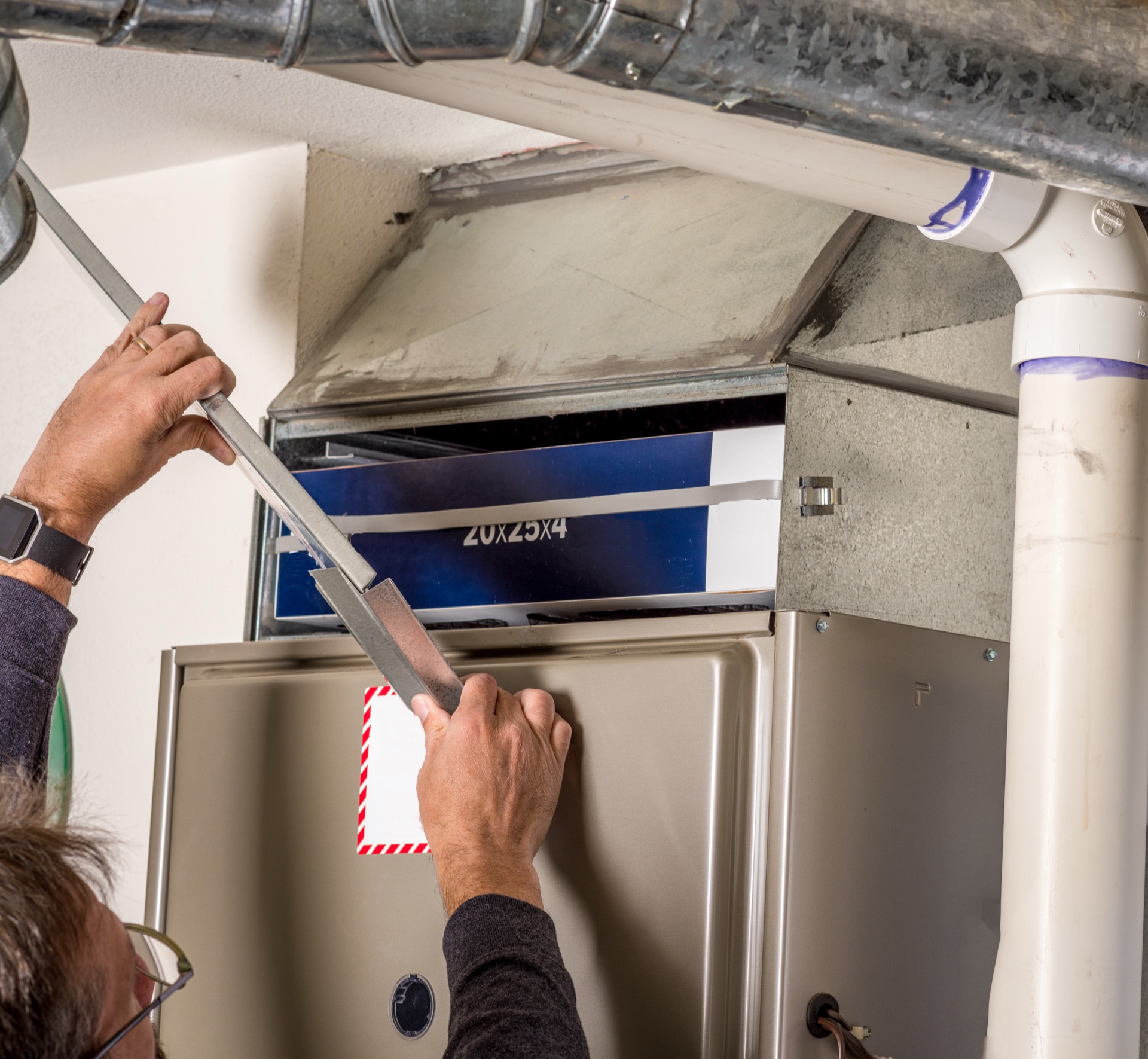 Technician opening HVAC ductwork panel during maintenance inspection