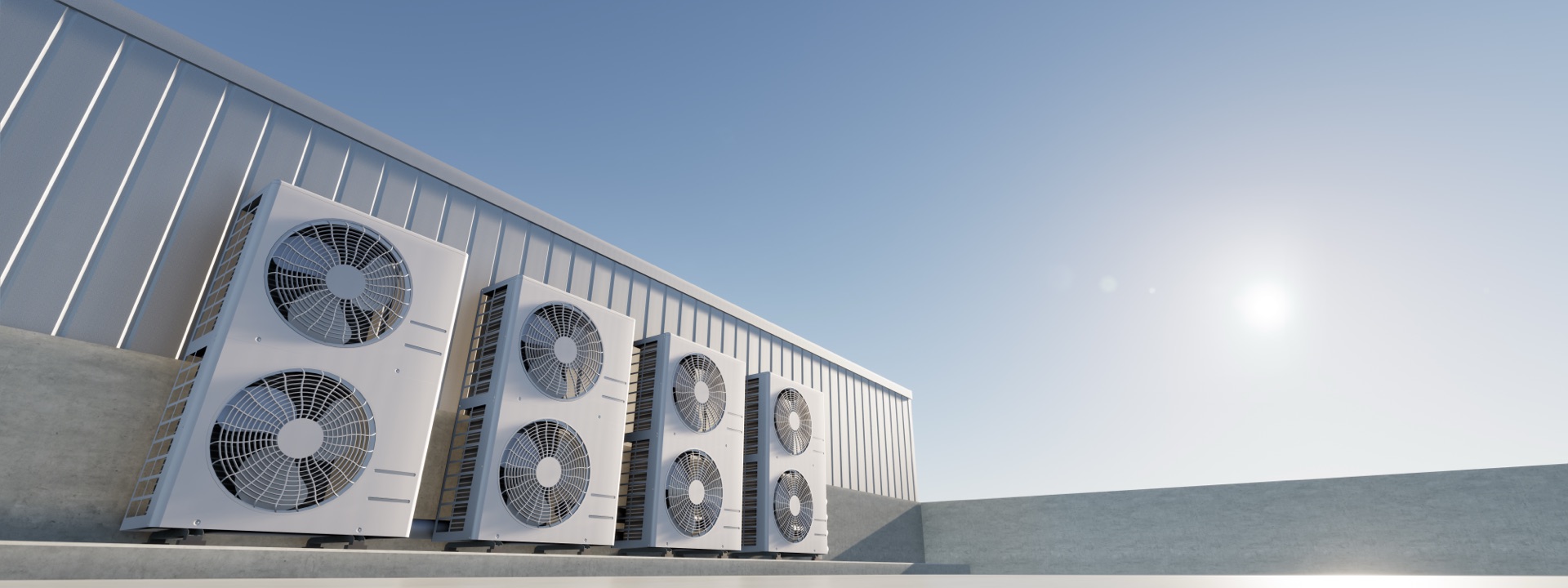 Industrial HVAC heat pump units mounted on concrete building exterior against clear sky